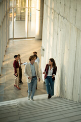 Obraz premium Business colleagues communicating while walking up modern office stairs