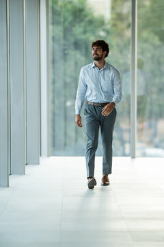 Young businessman walking confidently through office building hallway