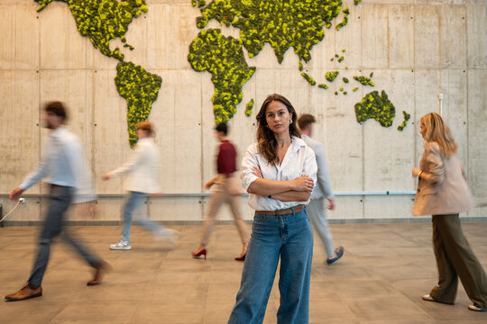 Confident businesswoman standing in busy global office environment