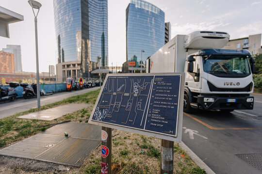 Milan, Italy - May 25, 2026: Information board with urban map and directions near modern buildings and parked vehicles in Milan, Italy