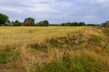 Obraz premium Wide view of harvested stubble field in rural countryside under cloudy sky 
