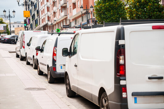 White vans are parked in row. Commercial fleet of vehicles