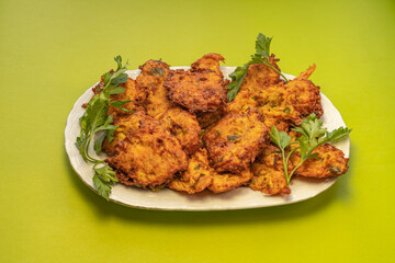 Fototapeta premium Traditional Turkish zucchini fritters served with fresh parsley on a white plate, featuring a crispy golden-brown texture and homemade preparation.