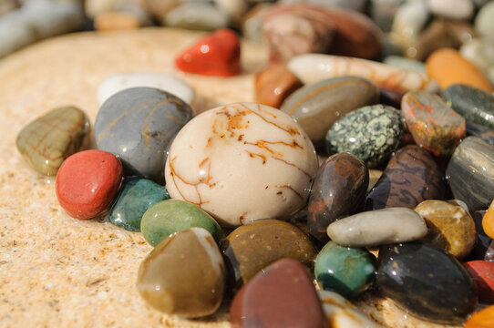 Multicolored smooth sea stones and pebbles on a sandy beach.