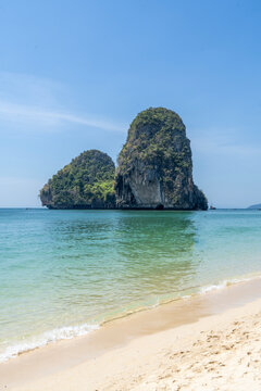 Idyllic tropical landscape showing a limestone karst island rising from the clear waters of the Andaman Sea at Phra Nang Beach, Krabi, Thailand.