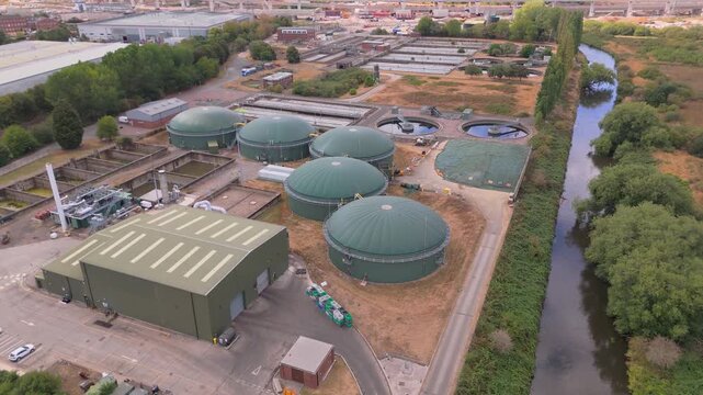 A drone orbit view of a small wastewater treatment plant with five anaerobic digester tanks used to produce heat and electricity from biomass to power the facility