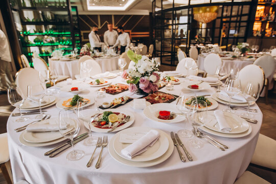 Elegant Dining Setup: A round dining table adorned with fine white linen, set with complete tableware, elegant glassware, and a beautiful floral centerpiece.