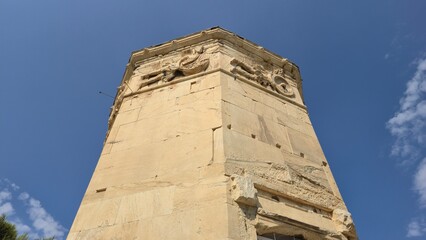 Ancient Agora, Athens, Greece - 8 July 2026. Low-angle view of the Horologion of Andronikos Cyrrhestes, with carved wind deities beneath the cornice. © Michael