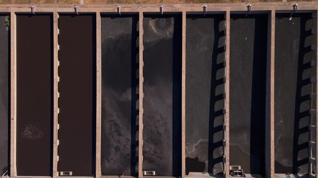 A rising drone view of aeration lanes at a waste water treatment plant which injects oxygen for bacteria to grow