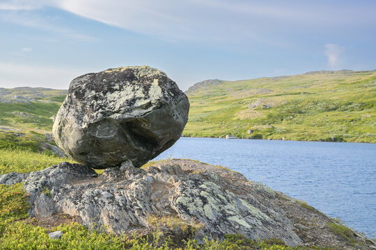 Close-up of a massive glacial erratic boulder balancing on a rock ledge in Norway