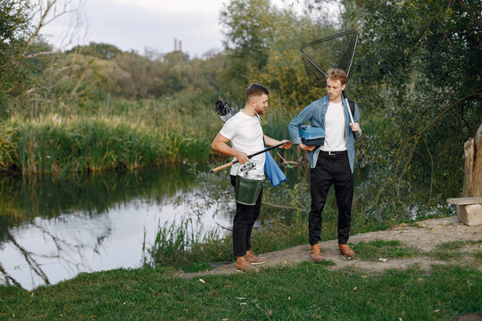 Two men walking and carrying fishing equipment outdoors