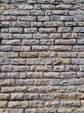 Straight front view of a historic grey limestone brick masonry wall with stacked stone blocks texture in Tallinn Old Town.