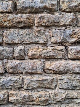 Straight front view of a historic grey limestone brick masonry wall with stacked stone blocks texture in Tallinn Old Town.