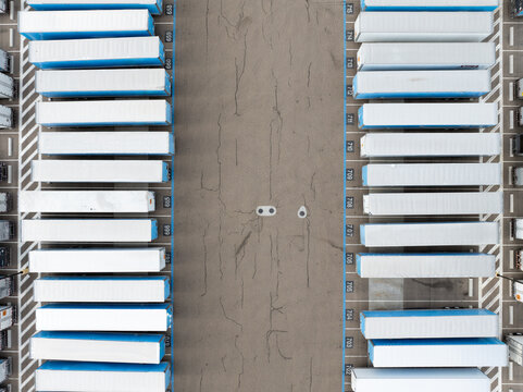 Aerial drone shot of semi-trailers parked in symmetrical rows