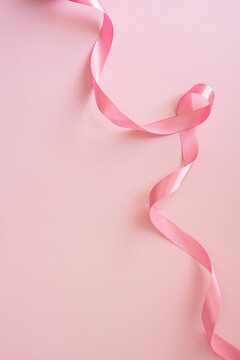 Pink ribbon for Breast Cancer Awareness Month on soft vertical pink background with elegant satin curl
