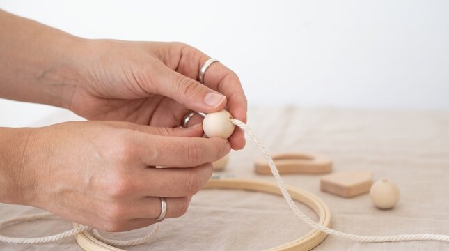 Threading a wooden bead onto a cotton string for a handmade craft project