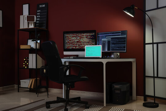 Remote work and coding late at night, empty home office desk with multiple screens showing programming code