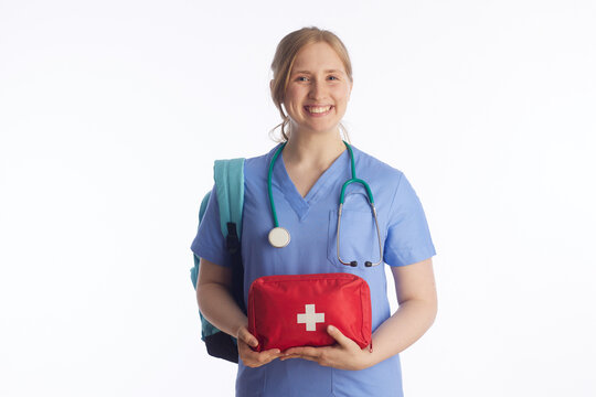 A young woman in medical scrubs and a stethoscope holds a first aid kit, representing emergency preparedness, basic life support training, and healthcare education.
