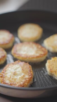 Cottage cheese pancakes fry in pan with golden crust and oil around them. Concept of homemade breakfast, simple recipe and dairy food