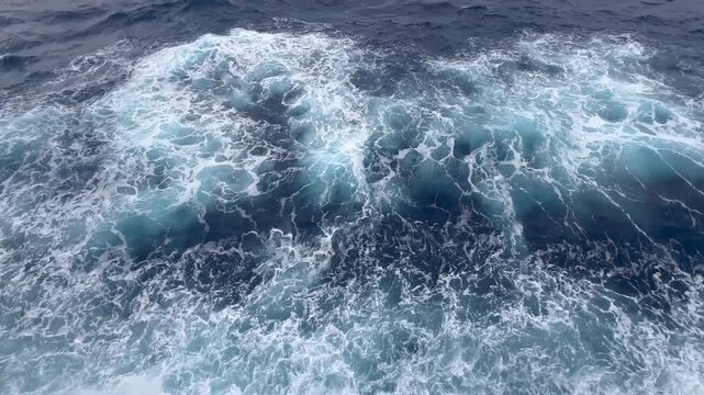 Footage from the bow of a cruise ship sailing through the Atlantic Ocean near Bermuda, showing the ship's bow cutting through the water and churning up white foam and turbulent waves.