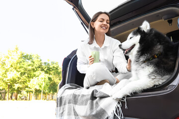 Pet friendly travel and road trip adventure, happy woman with husky dog sitting in car trunk enjoying nature © Pixel-Shot