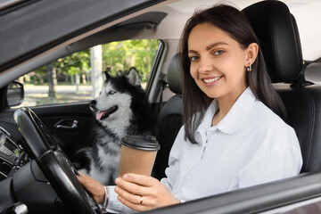 Pet friendly travel and road trip with dog, happy woman driving car with husky dog and coffee cup © Pixel-Shot