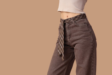Young woman in stylish brown jeans on beige background, closeup