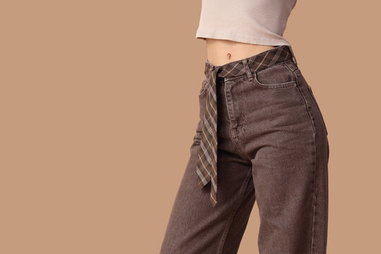 Young woman in stylish brown jeans on beige background, closeup