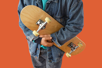 Young man with skateboard on orange background, closeup © Pixel-Shot