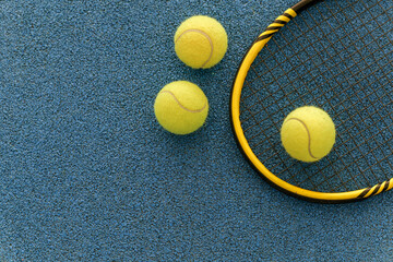 Naklejka premium Tennis racket and balls on a blue court surface, ready for a game