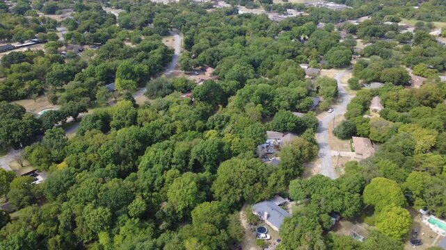 Extensive tree canopies shelter single family homes near Ten Mile Creek greenway. Paved residential streets, private fenced backyards border dense green woodland zones, DeSoto, Texas