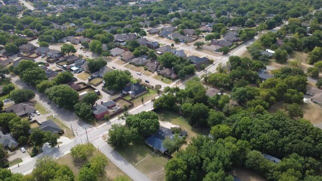 Curving neighborhood roadways weave through established Meadowbrook subdivisions. Colorful architectural roofs, custom swimming pools border lush green oak tree groves, DeSoto, Texas