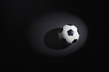 Naklejka premium A soccer ball on the rough concrete floor in the spotlight.