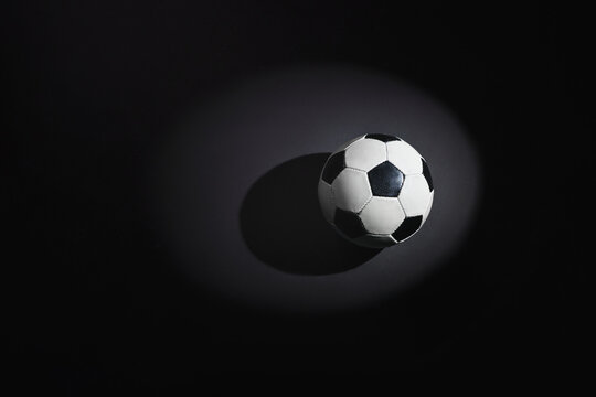 A soccer ball on the rough concrete floor in the spotlight.
