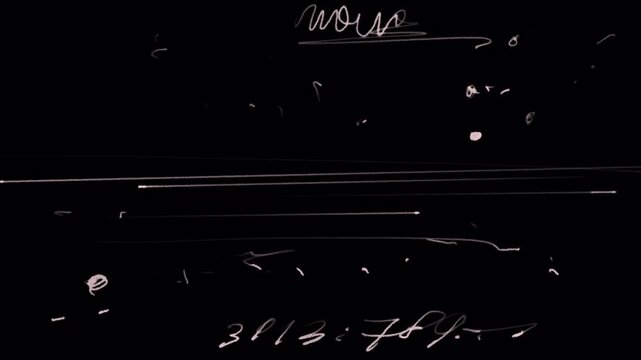 Old film strip with marks, words, letters, numbers and scratches on a black screen. 