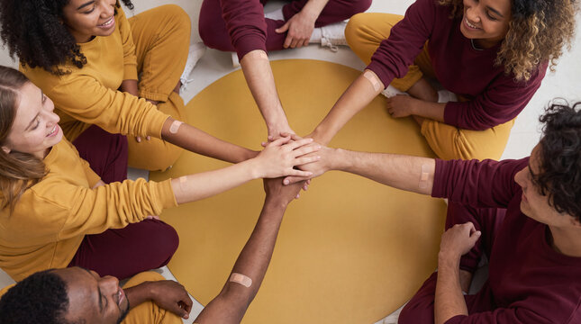 blood donation group stacking hands together in unity and teamwork during a community medical drive