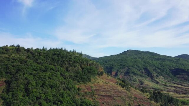 Aerial footage showcasing the lush green hills and distinctive red earth formations of the hinterland near Lac de Salagou, located in the Herault department of Occitanie, southern France.