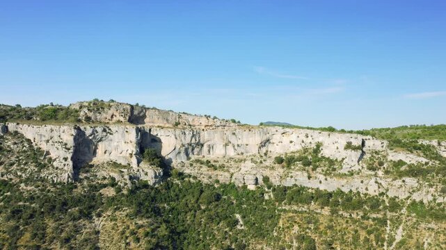 Aerial footage showcasing the dramatic limestone cliffs and rugged terrain of the Cirque de Navacelles, a natural amphitheater located in the Occitanie region of southern France.