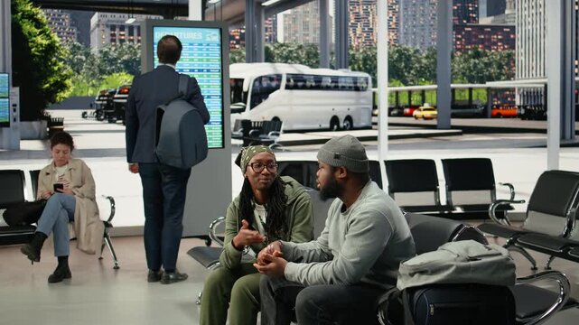 Travel companions talk in a bus station before departure, sharing conversation as the couple waits together in the coach terminal for their route.