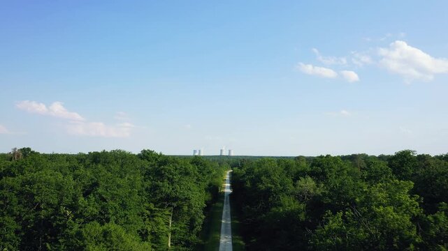 Aerial footage showing a straight road cutting through dense green forest with the Dampierre-en-Burly nuclear power plant visible on the horizon.