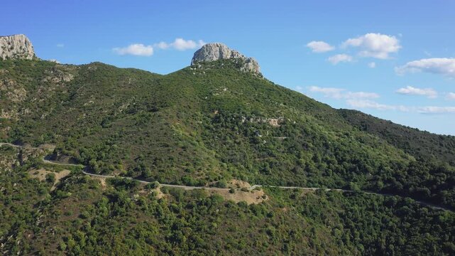 Aerial footage showcasing the lush, green hills and rugged landscape surrounding the town of Baunei in Sardinia, Italy.