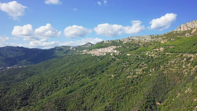 Aerial footage of Baunei, a picturesque village nestled in the lush green mountains of Sardinia, Italy.
