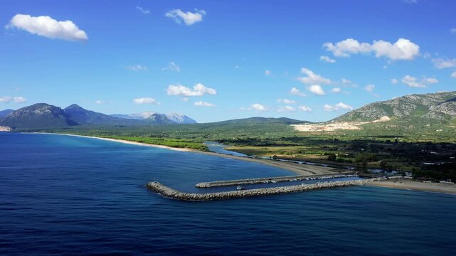 Aerial footage showcasing the entrance of the marina at Orosei, Sardinia, Italy. The sky is clear with scattered clouds, and there are no people visible in the scene.
