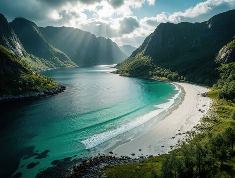 Aerial view of Hoddevik beach in Norway. Turquoise ocean waves crash on white sand shore between steep mountains. Scenic nordic landscape features green cliffs, sunny sky with light rays. Peaceful