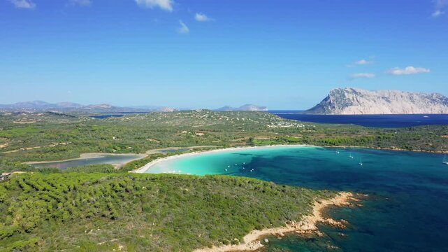 Aerial footage showcasing the stunning turquoise waters and white sandy shoreline of Cala Brandinchi beach near San Teodoro, Sardinia, Italy.