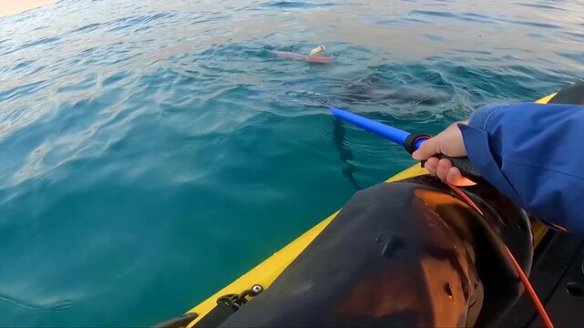 POV shot of an angler squid fishing with a jig lure from a kayak on the sea in Spain