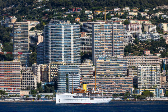 MONTE CARLO, MONACO - AUGUST 18, 2026: The historic luxury steam yacht SS Delphine moored in Port Hercule with the densely built skyline and residential skyscrapers of Monaco in the background.
