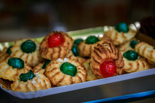 Freshly baked traditional Italian pasticcini alle mandorle almond cookies with red and green candied cherries on display at a bakery in Sanremo, Italy