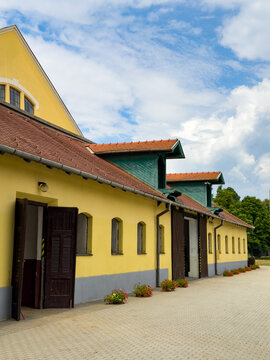 Yellow walls, green roofs. A building with yellow walls and green roofs under a blue sky. The doors are open, and flowers are visible.
