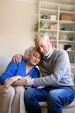 Senior couple sharing grief and finding comfort on sofa at home